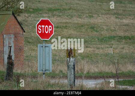 bright red Stop sign at a tank crossing and road junction on Salisbury Plain, Wiltshire Stock Photo