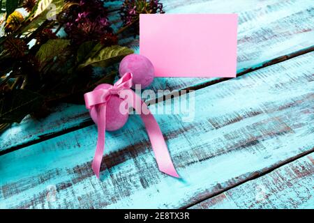 Pink painted easter eggs with decoration and a blank note on a wooden table. Selective focus. Easter decorations and celebration concept. Stock Photo