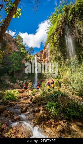Unrecognizable people enjoy waterfall descent using ropes Stock Photo