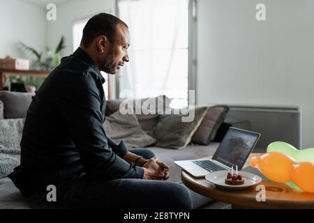 Middle aged man with birthday cake alone at home Stock Photo