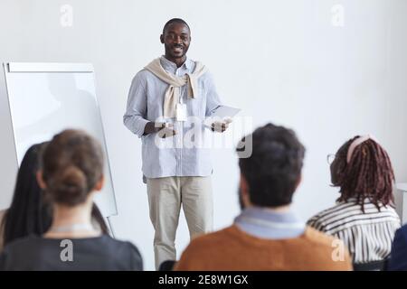 Portrait of smiling African-American business coach talking to audience at conference or education seminar, copy space Stock Photo