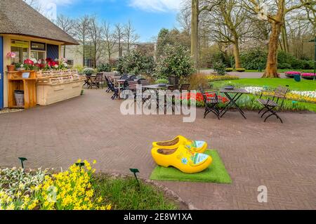 Keukenhof, Netherlands - April 4, 2016: Typical yellow dutch wooden shoes clogs or klompen, painted with windmill and flowerbed behind, Netherlands Stock Photo