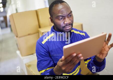 African warehouse worker using tablet computer before shipping in online trade Stock Photo