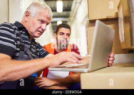 Two warehouse workers at the laptop computer plan package delivery service in online retail Stock Photo