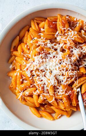 Gnocchetti sardi pasta in tomato sauce with cheese, gray background. Italian food concept Stock Photo