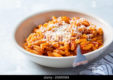 Gnocchetti sardi pasta in tomato sauce with cheese, gray background. Italian food concept Stock Photo