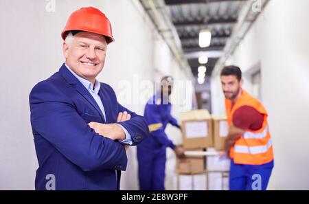 Self-confident entrepreneur as the boss of a haulage company in front of workers in the company Stock Photo