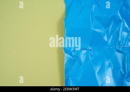 crumpled blue cardboard sheet of paper on green background, copy space Stock Photo