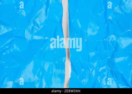 crumpled blue cardboard sheet of paper on white background, a4 sheet torn in half Stock Photo