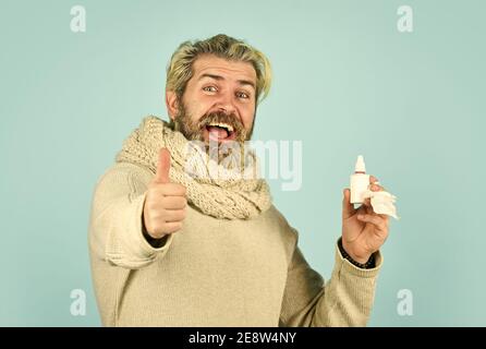 happy man says no to flu. coronavirus from china. immune system help during epidemic. healthcare in winter. best cold remedy. helpful nasal spray. man use nasal drops during course of disease. Stock Photo