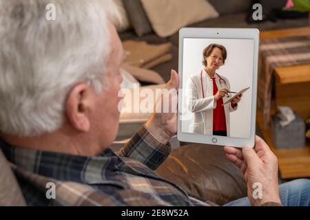 Symbolic image of telemedicine, elderly patient talks to a doctor in a video conference, from home, Stock Photo