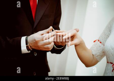 The groom puts the ring on the bride's hand. Hands of the newlyweds on the wedding day, close-up. The exchange of rings during the marriage. Stock Photo