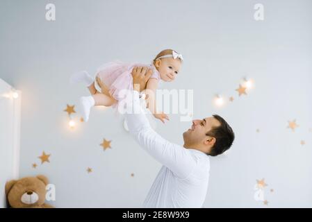 Father lifting baby girl. Happy father picks up and throws his lifting a small child. Home atmosphere, happy family laughing baby Stock Photo