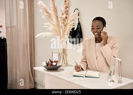 Smiling African entrepreneur talking on a phone in her boutique Stock Photo