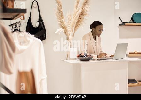 African American female entrepreneur using a laptop in her boutique Stock Photo
