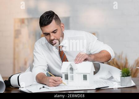 concentrated architect drawing on blueprint near house model Stock Photo