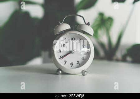 Selective focus of alarm clock show 8 o'clock or 8 a.m. on table with nature bokeh background. Time in life concept. Stock Photo