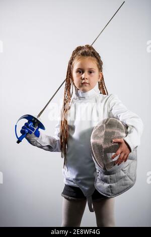 A child in a fencing costume is holding an epee. Girl learning fencing Stock Photo