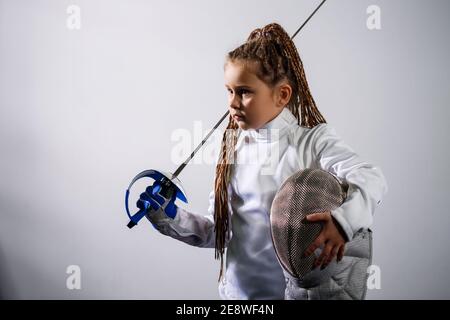 A child in a fencing costume is holding an epee. Girl learning fencing Stock Photo