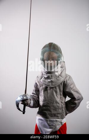 A child in a fencing costume is holding an epee. Girl learning fencing Stock Photo