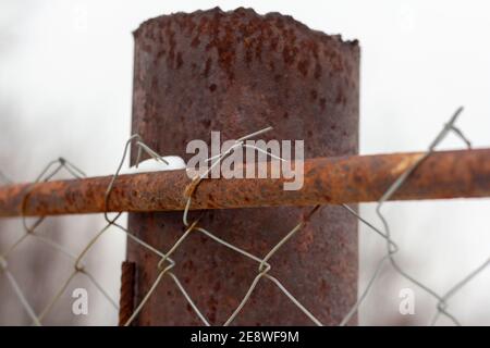 Close-up on a rusty metal pole rusty steel mesh chain link.An old fence. Stock Photo