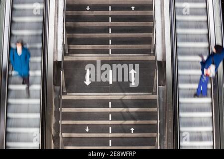 Berlin, Germany. 01st Feb, 2021. Two people are riding escalators in opposite directions in Berlin's main train station, with directional arrows painted on a staircase in between to keep them apart. (Motion blur due to long exposure time). Credit: Christoph Soeder/dpa/Ģ����ý Live News Stock Photo