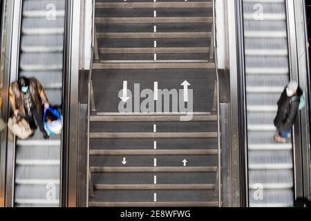 Berlin, Germany. 01st Feb, 2021. Two people are riding escalators in opposite directions in Berlin's main train station, with directional arrows painted on a staircase in between to keep them apart. (Motion blur due to long exposure time). Credit: Christoph Soeder/dpa/Ģ����ý Live News Stock Photo