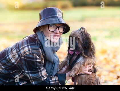 a woman walking with shih-tzu dog in the autumn park in sunny day Stock Photo