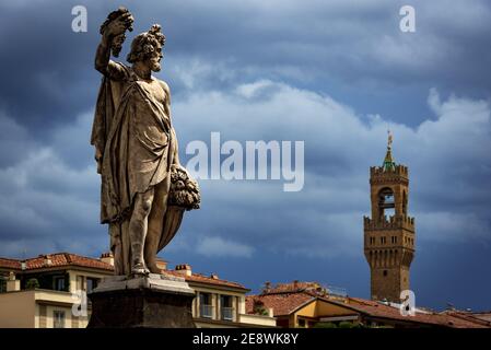 a statue depicting the allegory of Autumn on the Santa Trinita bridge of Florence with the town hall tower in the distance Stock Photo