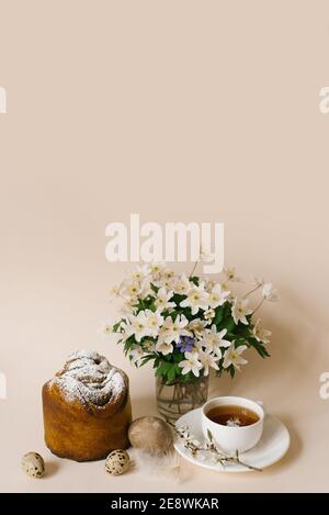 Easter composition with kulich and eggs with spring flowers on beige background. Easter holidays breakfast concept. Stock Photo