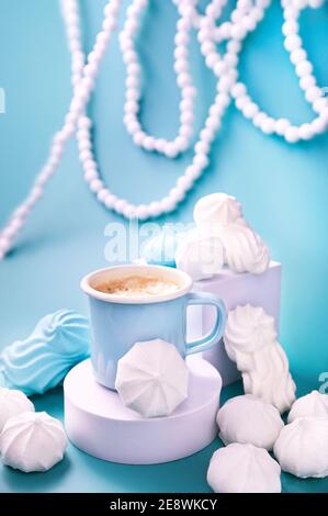 Meringues of different colors on a blue background and coffee. Espresso cup with foam. A creative shot of protein and sugar cookies. High quality photo. Copy space. Vertical photo Stock Photo