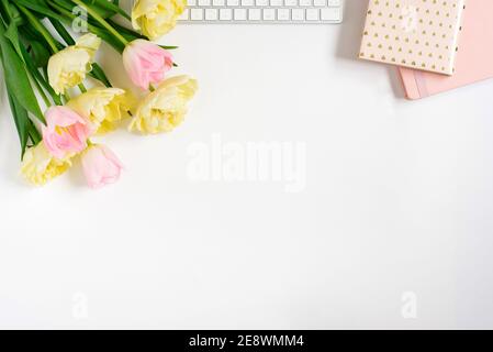 Springtime flat fly with keyboard, notebooks, bunch of pink tulips on a light background. Spring concept for a blog. Greeting Card for Valentine's Day Stock Photo