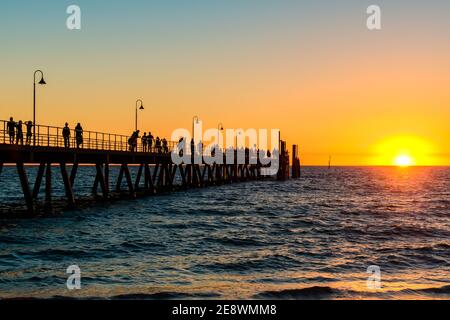 Glenelg Beach jetty with people walking along at sunset during summer evening Stock Photo