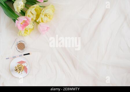 Cosmetic pen and pink yellow tulips on beige desk background. Template for advertising or visualization of blog with copy space, text place. Certifica Stock Photo