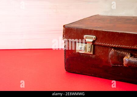 Suitcase vintage, old fashioned. Leather retro travel luggage on red floor, copy space. Tourism, holiday vacation packing concept Stock Photo