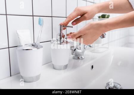 cropped view of woman using soap dispenser in bathroom Stock Photo