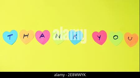 colorful sticky paper note with hearth shape write thank you on yellow foam board background Stock Photo