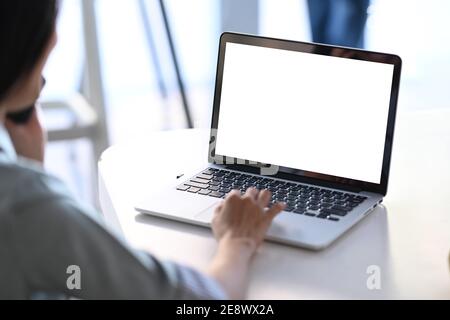 Rear view of businesswoman talking on mobile phone and using laptop computer searching information at office. Stock Photo