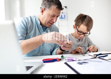 Father and son repairing an electrical outlet while sitting at a desk. Learn for life concept Stock Photo