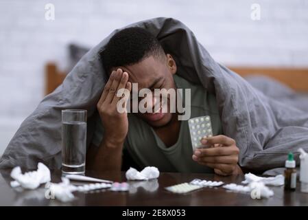 Sick Guy Having Headache And Fever Taking Pills In Bedroom Stock Photo