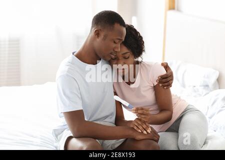 Upset black couple holding negative pregnancy test Stock Photo