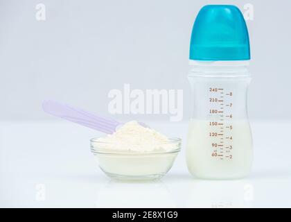 Powdered Milk, Baby Formula with spoon infant formula in bowl and bottle for feeding baby on white table. dairy food for baby Stock Photo