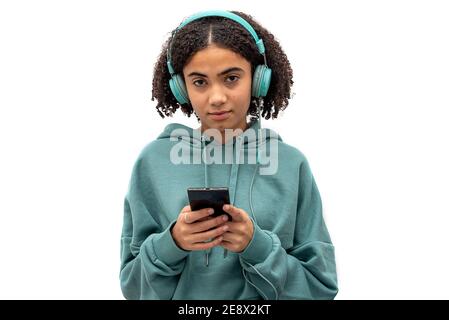 Black teenager looking at camera while using smartphone and listening to music isolated on white background Stock Photo
