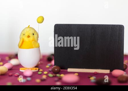 Decorative chick, easter sweets and blackboard with copy space. Easter holiday concept Stock Photo