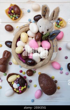 Top view of easter bunny basket with almonds, chocolate eggs and other easter sweets Stock Photo