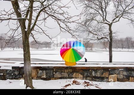 A man carrying a colorful umbrella visits Constitution Gardens during a snowy day in Washington, D.C. Stock Photo