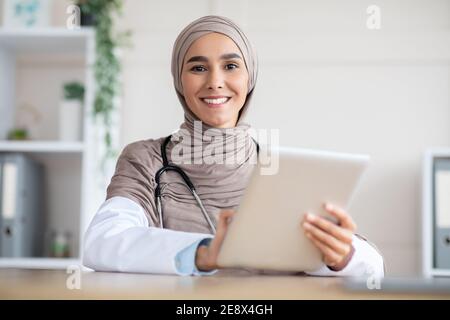Smiling female doctor using digital tablet, clinic interior Stock Photo