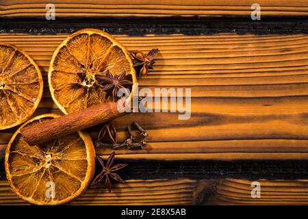 Aromatic winter Christmas spices on wood background. Cinnamon stick, clove, star anise, dried orange slices  Empty room for text. Stock Photo