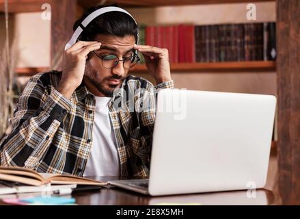 Tired Student Sitting At Laptop And Books Learning In Library Stock Photo