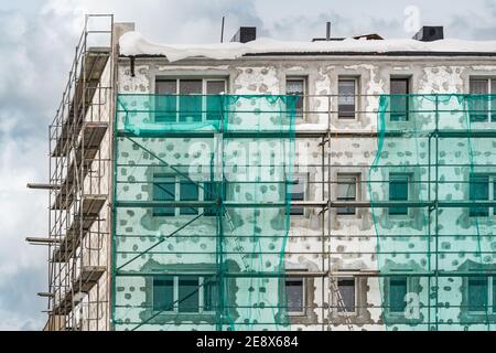 Renovation process of old multistory building. Tall building under construction with scaffolds. Stock Photo